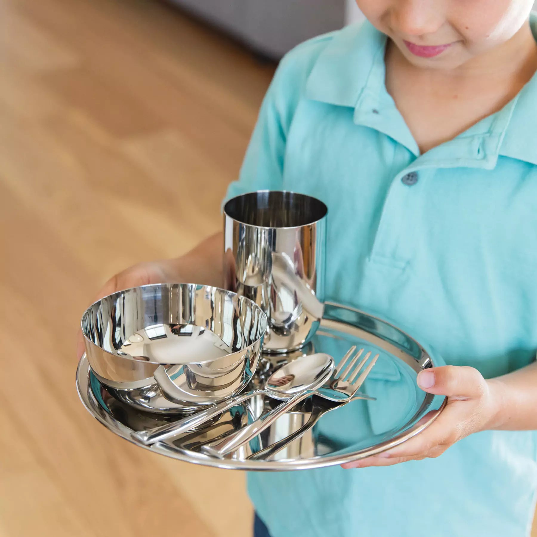 Boy holding stainless dishes for older kids - plate, bowl, cup, fork, and spoon in classic or silver color